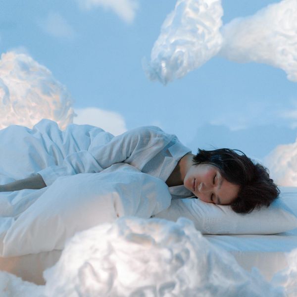 Person meditating peacefully in a bright, airy room with light blue tones.